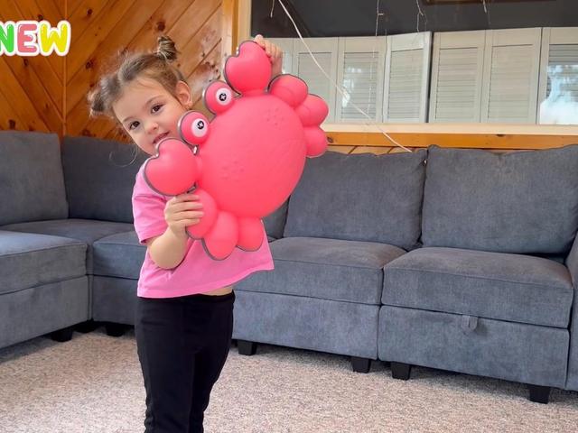 A girl holding a crab stepping stone in a living room