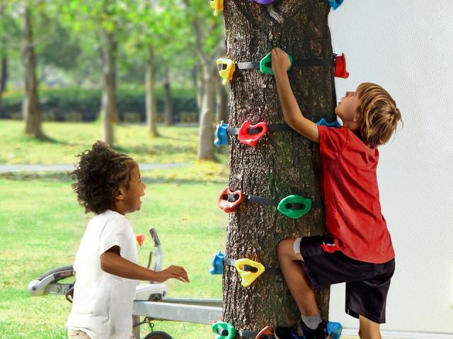 Two children climbing a trunk on strap-on holds