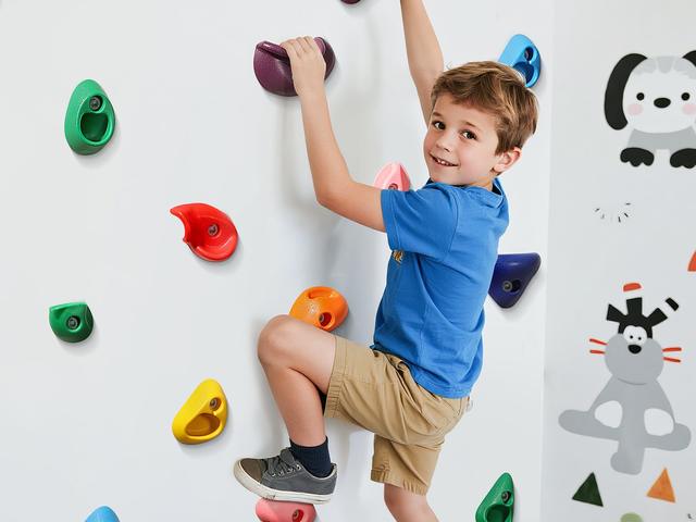 A boy climbing a plywood panel set with bright resin holds