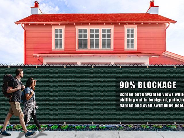 A knitted privacy screen stretched along a backyard fence
