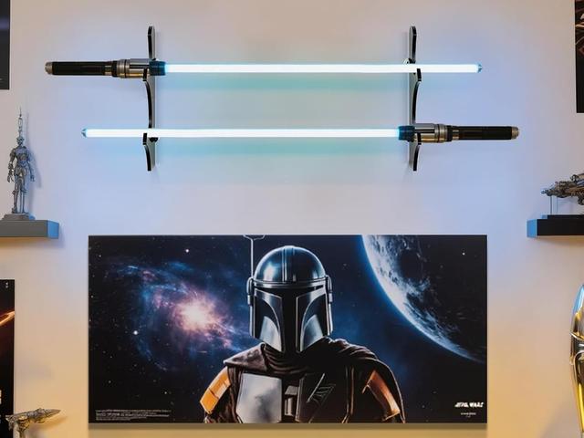 Two light sabers resting on a black wall mount above a desk